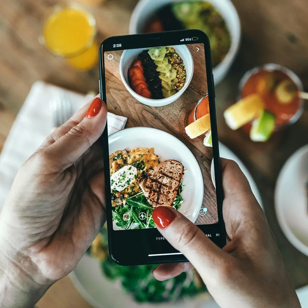 Person using phone to take photo of food on a table