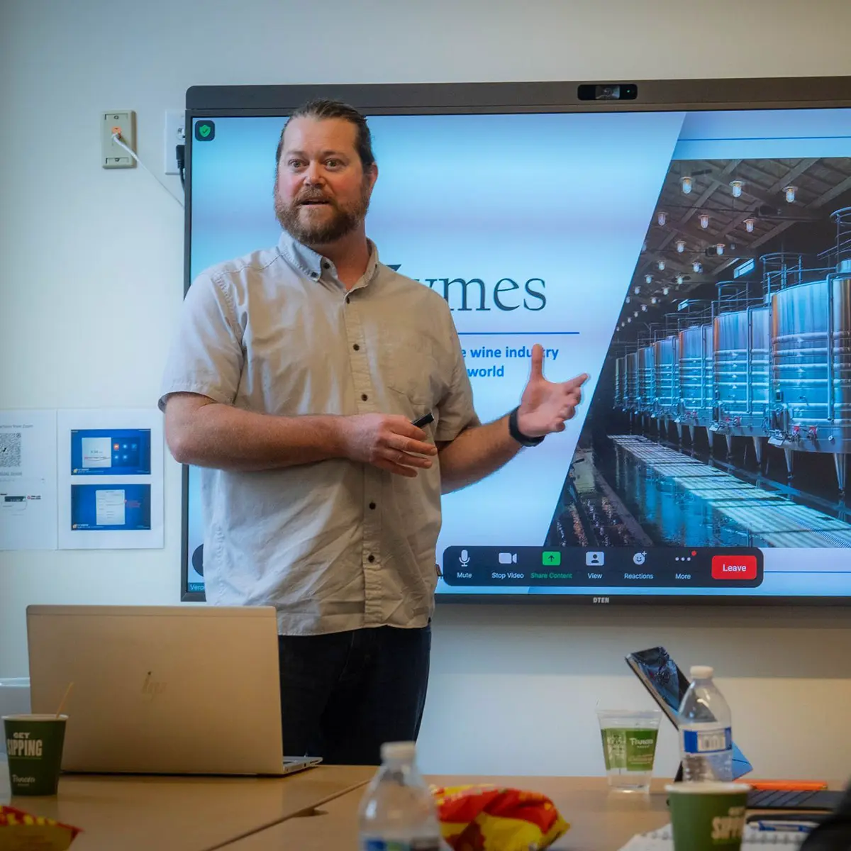 Man speaking at a meeting in front of a large tv screen