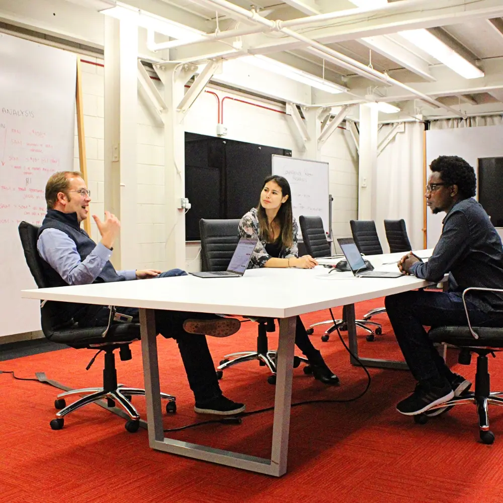 Three people sitting and talking in a meeting room