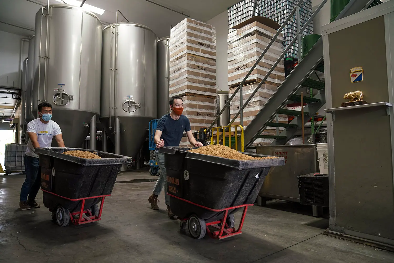 Two men pushing bins of food