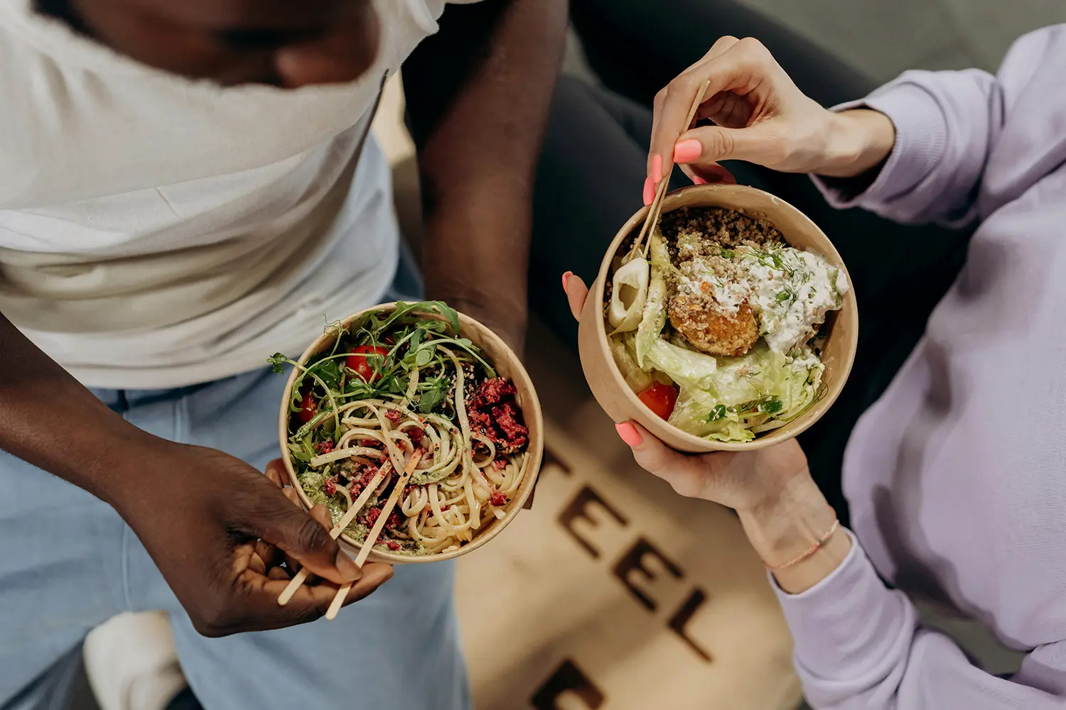 People holding bowls of food and eating with chopsticks