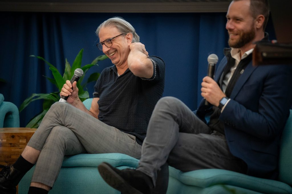 Two men sitting on stage laughing